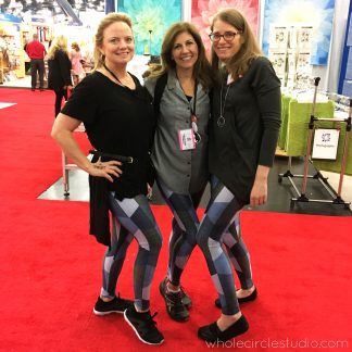 Showing off our Hexie Blues Leggings (pants that look like a quilt—but it's not!). Sheri of Whole Circle Studio with Just Wanna Quilt — Quilt Army members at International Quilt Market 2018 in Houston, Texas